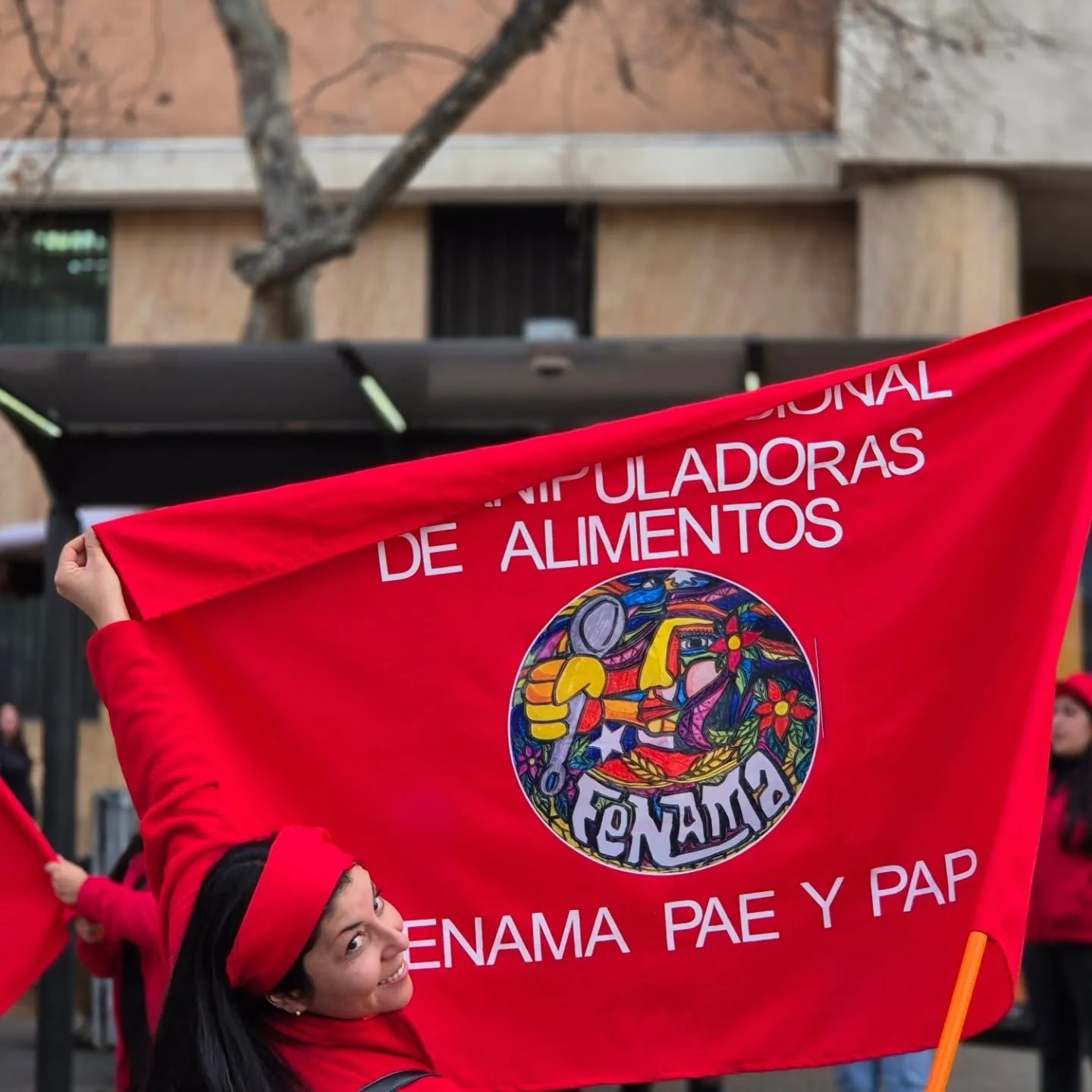 Manipuladora levanta la bandera roja de FENAMA PAE y PAP en una marcha